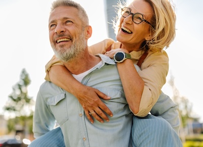 A joyful couple shares a moment of laughter and love while enjoying the sunshine in an urban setting, representing happiness and connection in their relationship.