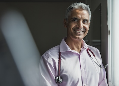 Portrait of a mature Asian doctor smiling at the camera.