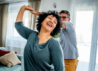 Happy playful mature couple dancing at home